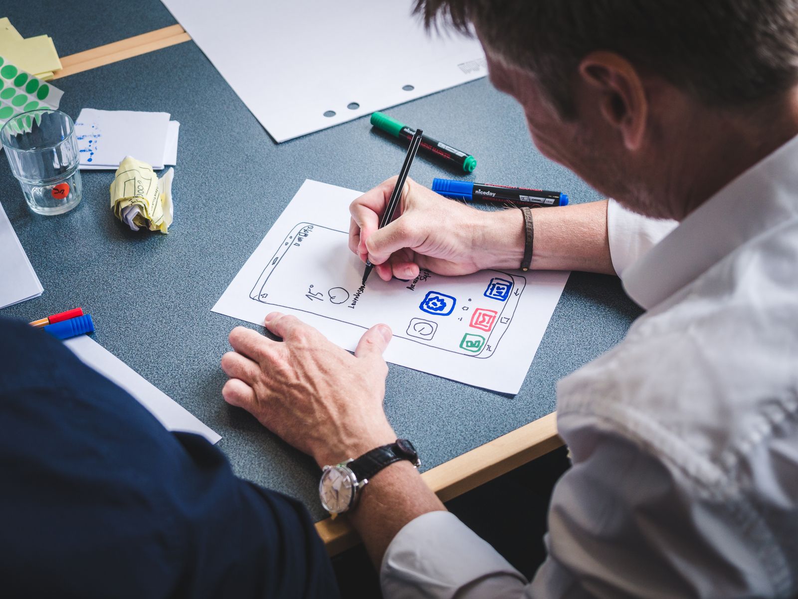 Designer sketching a mobile app prototype at a studio desk